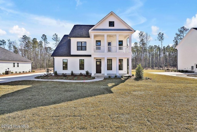 view of front of property featuring a balcony, covered porch, a front lawn, and central air condition unit