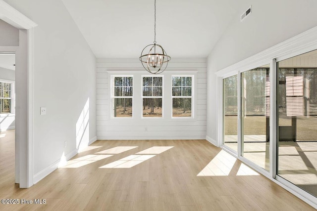 unfurnished sunroom featuring vaulted ceiling, plenty of natural light, and a notable chandelier