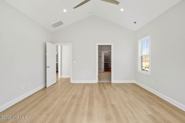 unfurnished bedroom with ceiling fan, a walk in closet, vaulted ceiling, and light wood-type flooring