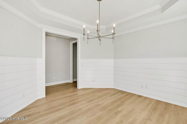 empty room with a notable chandelier, crown molding, light hardwood / wood-style floors, and wood walls