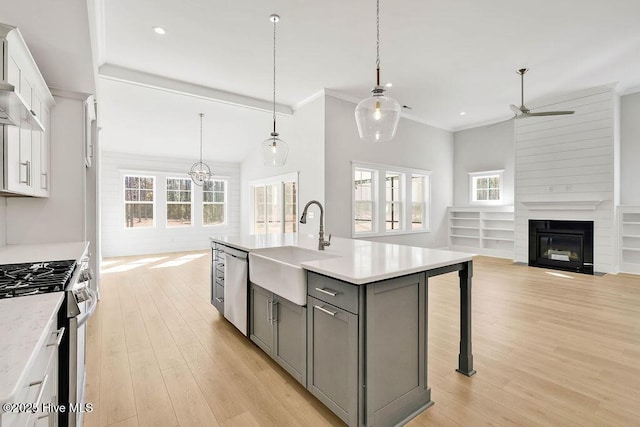 kitchen featuring gray cabinets, a breakfast bar area, appliances with stainless steel finishes, white cabinetry, and an island with sink