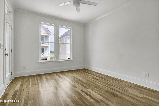 empty room with a ceiling fan, crown molding, baseboards, and light wood-type flooring