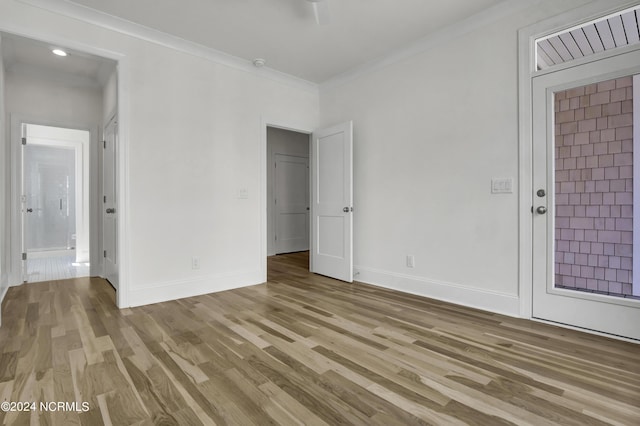 unfurnished bedroom featuring light wood-type flooring, baseboards, and ornamental molding