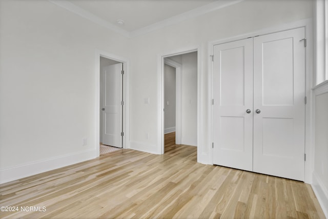 unfurnished bedroom featuring light wood-type flooring, baseboards, a closet, and ornamental molding