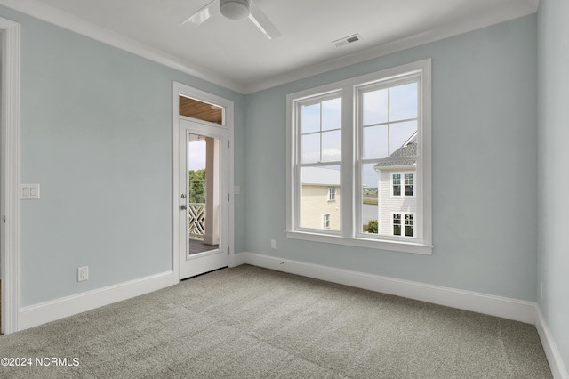 carpeted spare room featuring visible vents, baseboards, ceiling fan, and crown molding