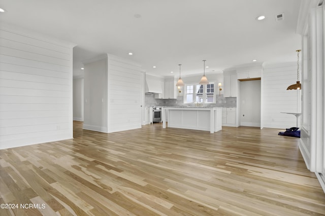 unfurnished living room with recessed lighting, wooden walls, and light wood finished floors