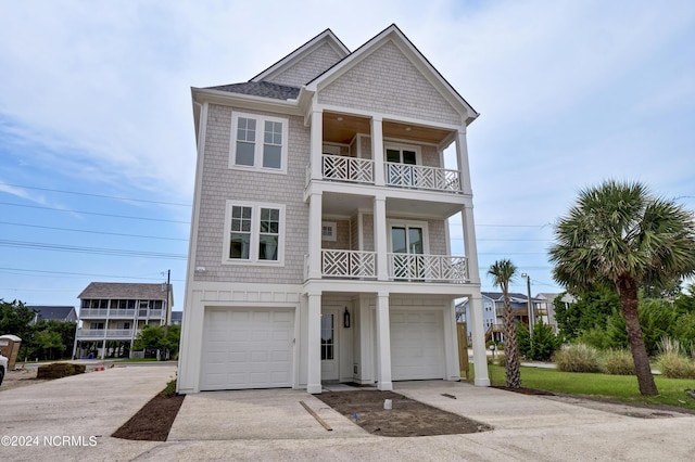 coastal home featuring a garage, driveway, a balcony, and board and batten siding