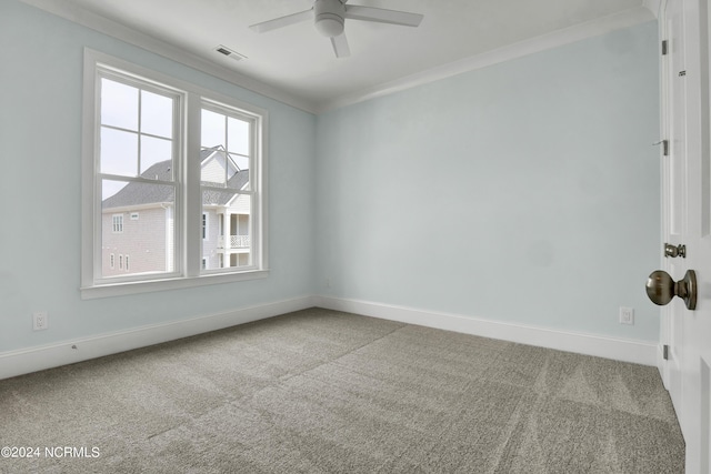 carpeted empty room with ceiling fan, visible vents, baseboards, and ornamental molding