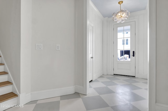 foyer with tile patterned floors, baseboards, an inviting chandelier, and stairs