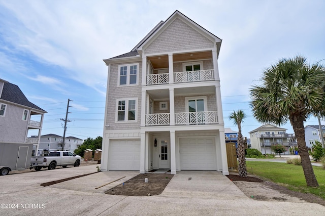 coastal home featuring a balcony, a garage, and driveway