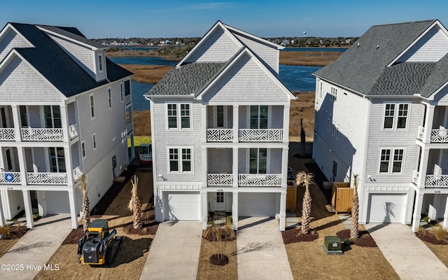 raised beach house featuring driveway, an attached garage, and roof with shingles