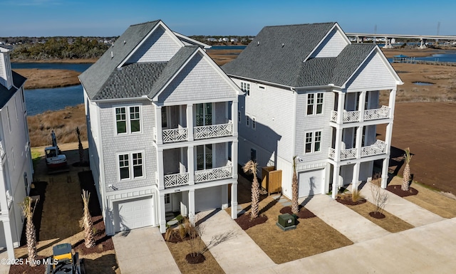 beach home featuring a garage, roof with shingles, and driveway