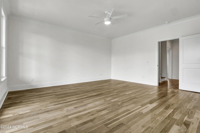 spare room featuring ornamental molding, baseboards, ceiling fan, and wood finished floors