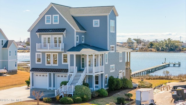 coastal home with a standing seam roof, metal roof, concrete driveway, and stairs