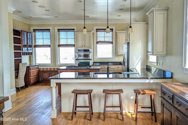 kitchen featuring stainless steel appliances, a sink, light wood-style flooring, and a kitchen bar