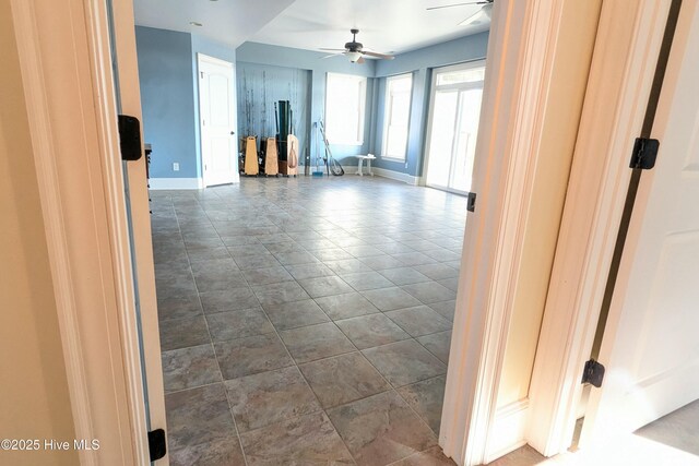 spare room with dark tile patterned flooring, ceiling fan, and baseboards