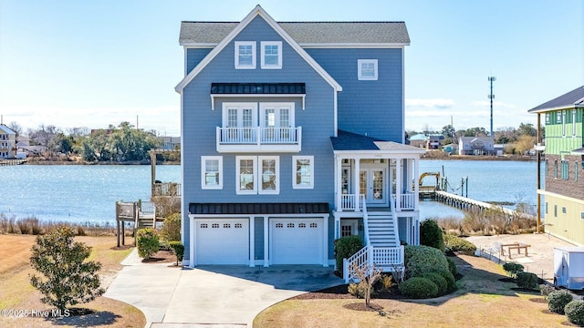 coastal home with a water view, driveway, a balcony, and stairs