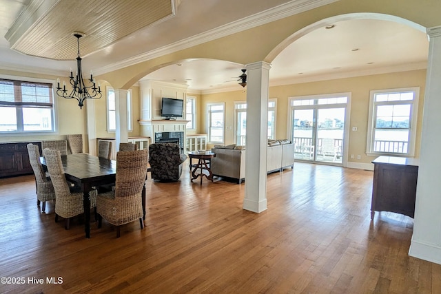 dining room featuring a healthy amount of sunlight, a fireplace, hardwood / wood-style floors, and ceiling fan with notable chandelier