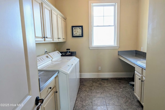 washroom featuring washing machine and dryer, cabinet space, and baseboards