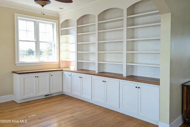 interior space with wood finished floors, visible vents, baseboards, built in features, and crown molding