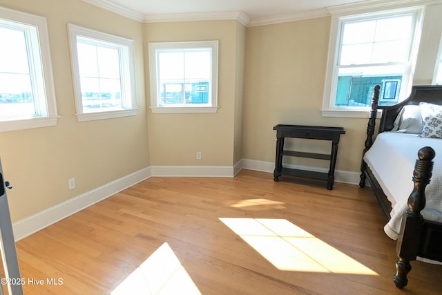 bedroom featuring light wood-style floors, baseboards, and crown molding