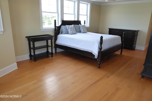 bedroom featuring ornamental molding, light wood-style flooring, and baseboards