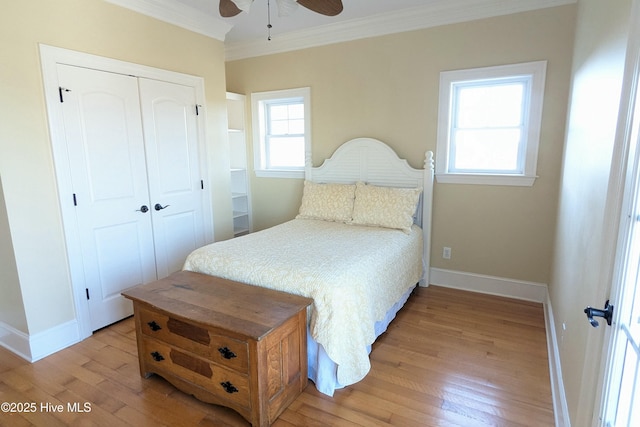 bedroom featuring a closet, ornamental molding, light wood-style floors, a ceiling fan, and baseboards