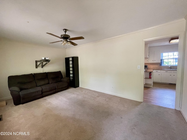 unfurnished living room with crown molding, ceiling fan, a sink, and carpet flooring