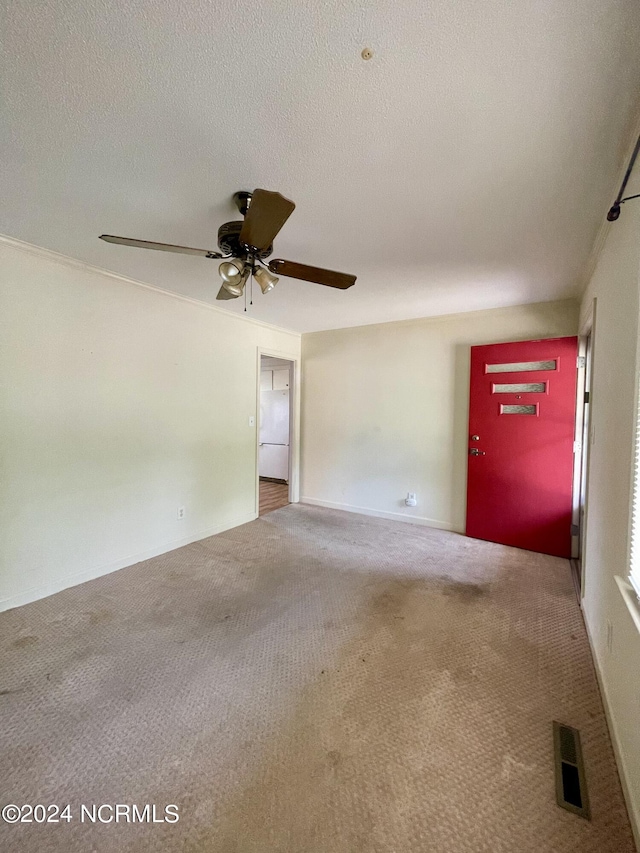 spare room featuring carpet, visible vents, ceiling fan, and a textured ceiling