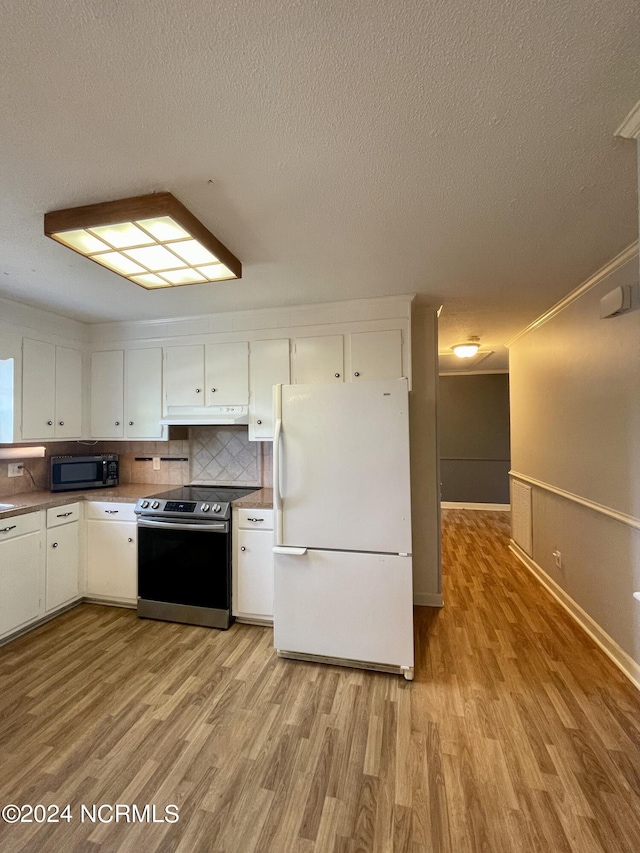 kitchen with light wood finished floors, freestanding refrigerator, under cabinet range hood, stainless steel range with electric stovetop, and white cabinetry