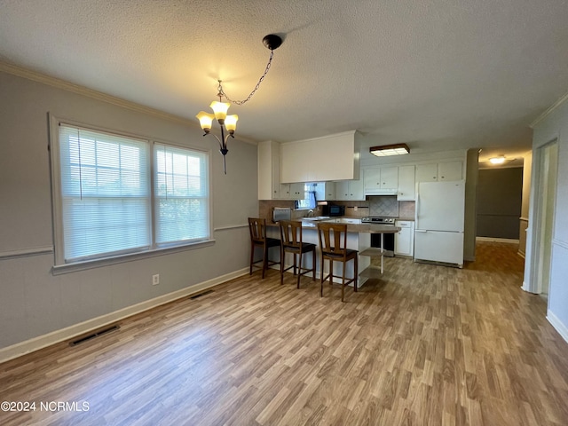 kitchen featuring visible vents, freestanding refrigerator, a peninsula, stainless steel electric range, and a notable chandelier