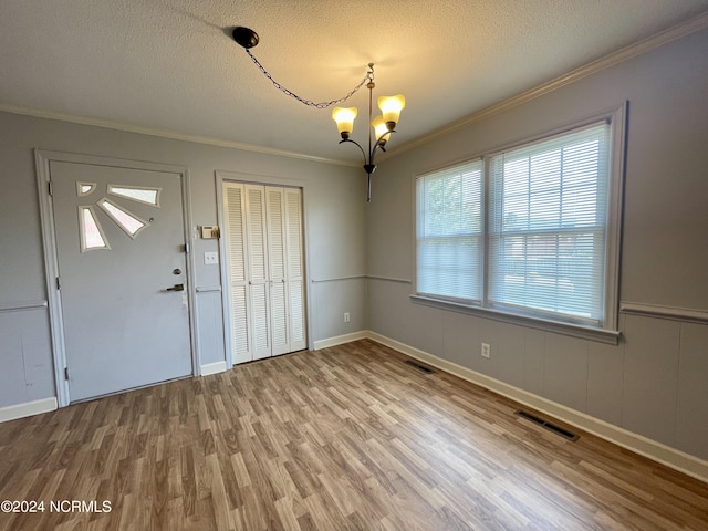 foyer featuring crown molding, visible vents, a textured ceiling, wood finished floors, and a chandelier