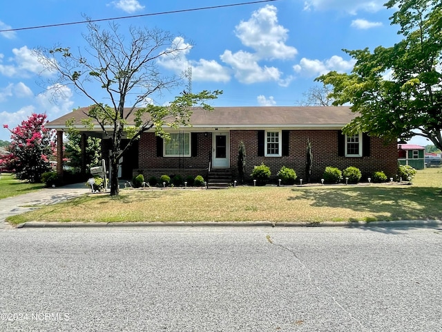 single story home featuring a front yard, brick siding, and driveway