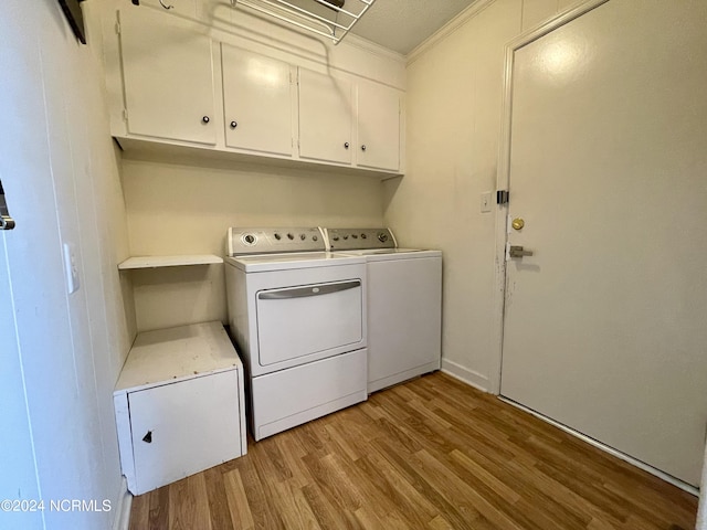 laundry room featuring ornamental molding, light wood-type flooring, cabinet space, and washer and clothes dryer