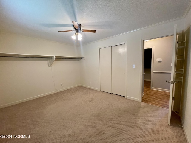 unfurnished bedroom with a textured ceiling, ornamental molding, a closet, and light colored carpet