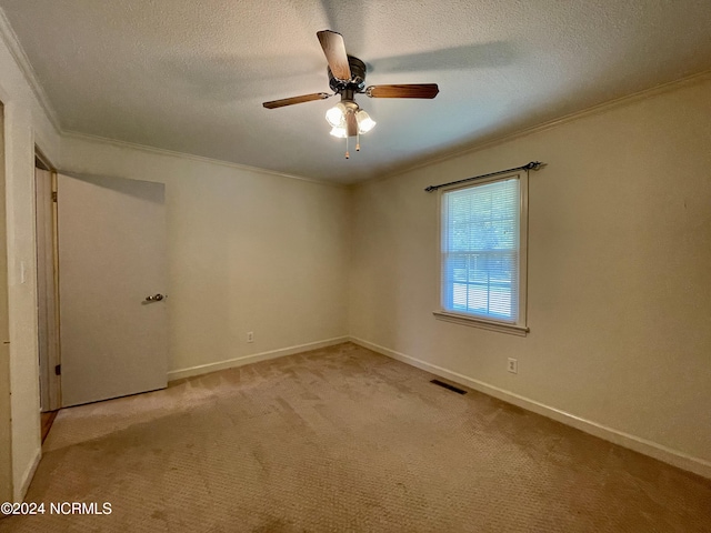 carpeted empty room featuring a textured ceiling, baseboards, visible vents, and crown molding