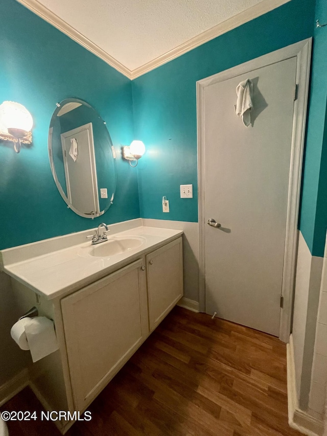 bathroom featuring crown molding, vanity, a textured ceiling, and wood finished floors