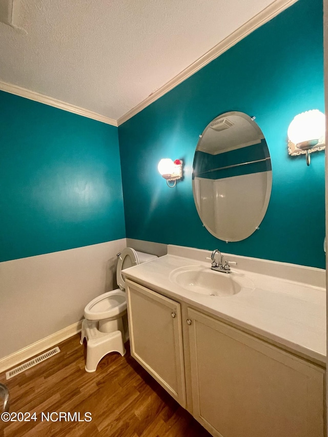 bathroom featuring a textured ceiling, wood finished floors, vanity, visible vents, and ornamental molding