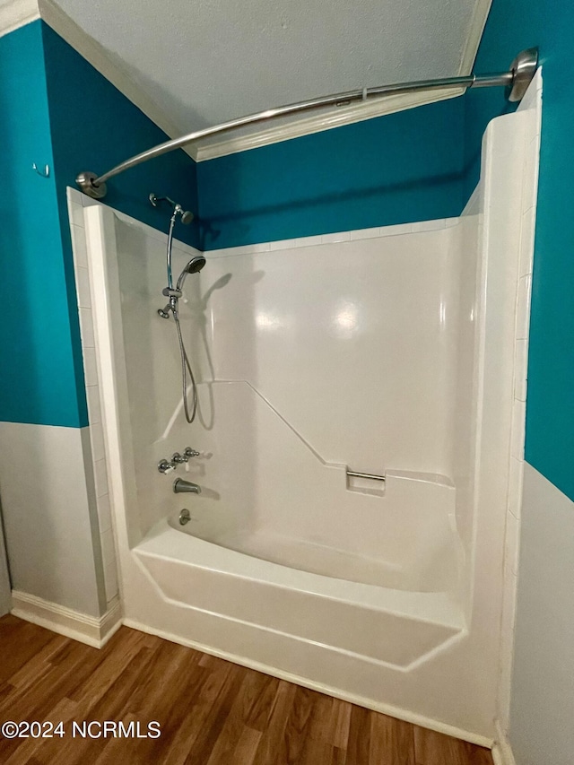 bathroom with a textured ceiling, wood finished floors, and shower / tub combination