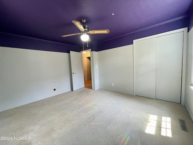 unfurnished bedroom with a closet, carpet, visible vents, and a ceiling fan