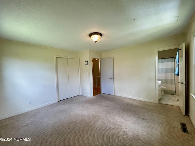 unfurnished bedroom with visible vents, baseboards, a closet, carpet, and ensuite bath