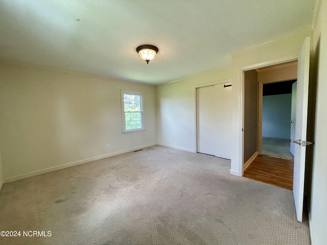 unfurnished bedroom featuring carpet, a closet, visible vents, ornamental molding, and baseboards