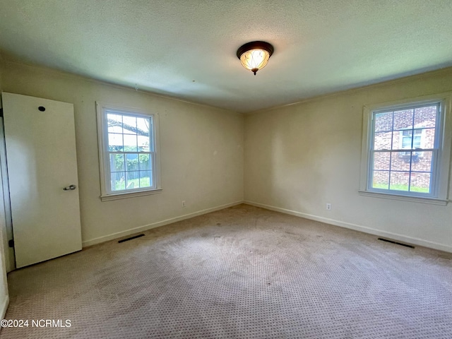 empty room with carpet floors, visible vents, and a textured ceiling