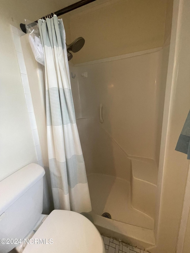 full bathroom featuring toilet and a shower stall