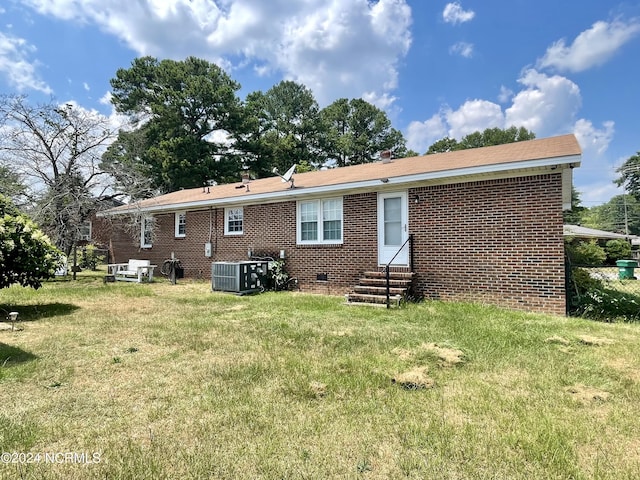 back of house featuring entry steps, cooling unit, brick siding, crawl space, and a lawn