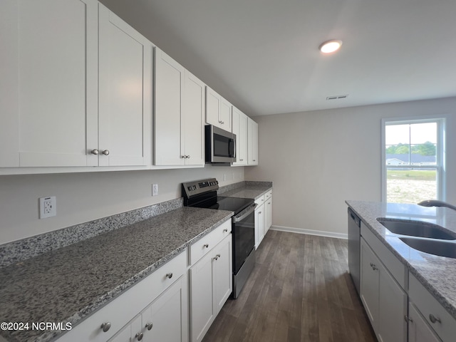 kitchen with sink, white cabinetry, stainless steel appliances, dark hardwood / wood-style flooring, and stone countertops