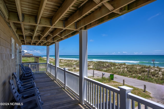 wooden terrace with a water view and a view of the beach