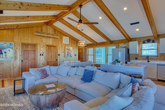 living room featuring vaulted ceiling with beams, sink, a healthy amount of sunlight, and ceiling fan with notable chandelier