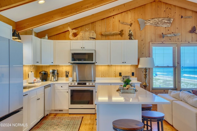 kitchen with vaulted ceiling with beams, a kitchen island, white cabinetry, and appliances with stainless steel finishes