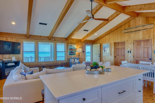 kitchen featuring white cabinets, lofted ceiling with beams, a kitchen island, and ceiling fan